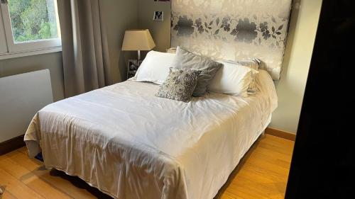 une chambre avec un lit avec des draps blancs et des oreillers dans l'établissement T4 HAUT DE GAMME ROUTE DES SANGUINAIRES, à Ajaccio