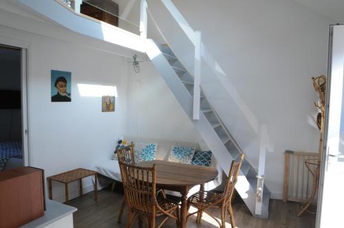 une salle à manger avec une table et des chaises sous un escalier dans l'établissement L'équipage - Hyper centre, charme et calme à deux pas de la mer, à Cabourg
