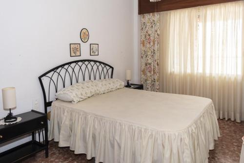a bedroom with a bed with a white bedspread and a window at Arensol Esc-A, 13º-51 in Cullera