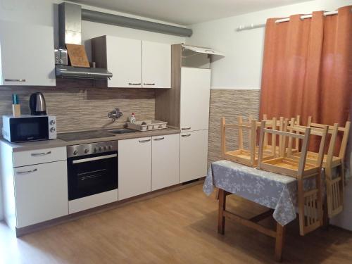 cocina con armarios blancos, fogones y mesa en Čebelica, apartma 101, Terme Čatež, en Brežice