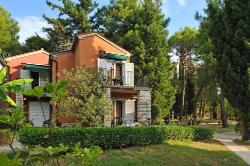 an orange house with a balcony and trees at Holiday Park Vile - Terme Krka in Strunjan