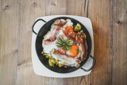 a pan filled with meat and vegetables on a table at Familyparadies GAMPLALM in Lana