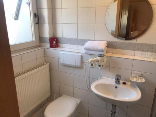 La salle de bains est pourvue d'un lavabo, de toilettes et d'un miroir. dans l'établissement Self-check-in Ferienwohnungen & Apartments am Bergsee, à Triberg