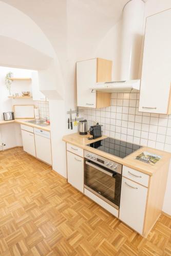 a kitchen with white appliances and a wooden floor at Zum Grazer Uhrturm in Graz