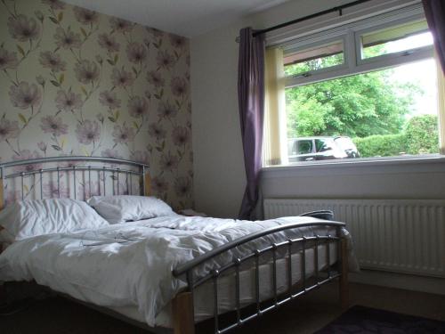 a bedroom with a bed in front of a window at Dingieshowe Cottage in Lennoxtown