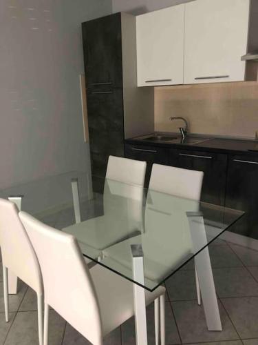 a glass table and white chairs in a kitchen at LE STELLE DI SAN LORENZO appartamento indipendente in Decimomannu