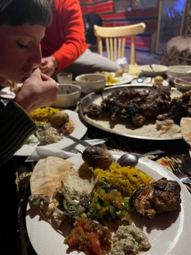 a person sitting at a table with plates of food at Happy Bedouin House Petra in Al Ḩayy