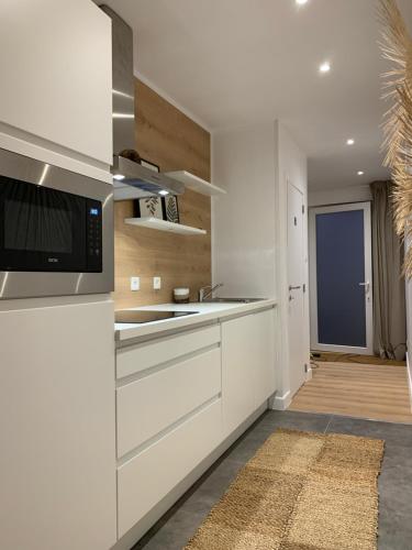 a white kitchen with a sink and a microwave at Une parenthèse à la Sarte (wellness) in Huy