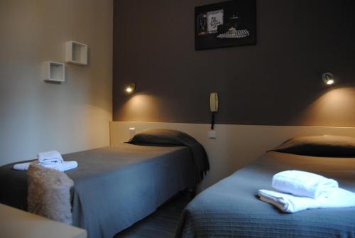 Habitación con 2 camas y teléfono en la pared. en Hôtel Acropolis en Lourdes