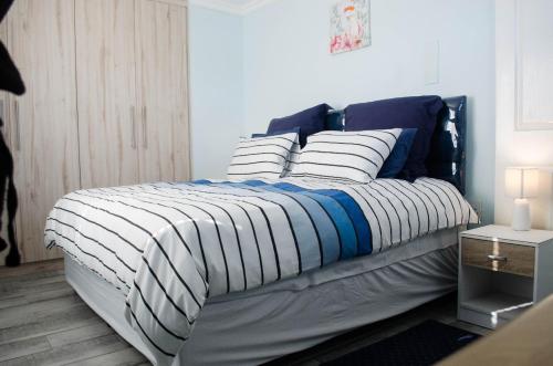 un letto con coperta e cuscini blu e bianchi di Birds Holiday Accommodation 2 a Città del Capo