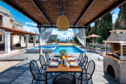 a patio with a table and chairs next to a pool at Aileen Villa in Koskinou