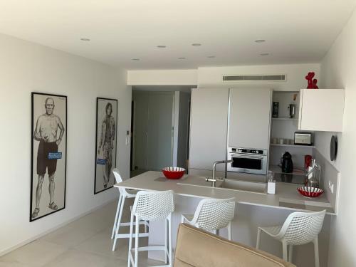 eine weiße Küche mit weißen Stühlen und eine Kücheninsel in der Unterkunft APPARTEMENT 2 chambres vue mer panoramique, proche Croisette Cannes in Vallauris