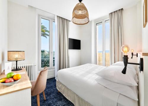 a hotel room with a bed and a table with a bowl of fruit at Hotel Le Suquet Cannes in Cannes