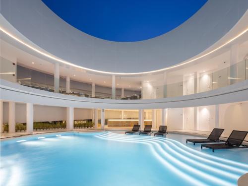 a large swimming pool in a building with chairs at G Nimman Chiang Mai in Chiang Mai