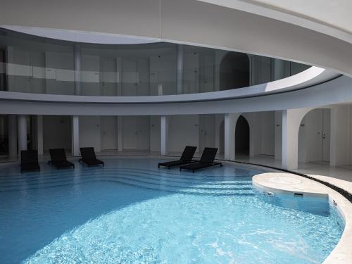 a large swimming pool with chairs in a building at G Nimman Chiang Mai in Chiang Mai