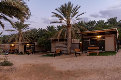 a small hut with a bench and palm trees at Ras Hasita in H̱aẕeva