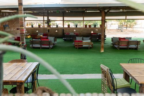 a patio with tables and chairs and green grass at Ras Hasita in H̱aẕeva