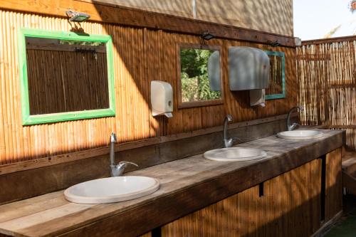 a bathroom with three sinks and two mirrors at Ras Hasita in H̱aẕeva
