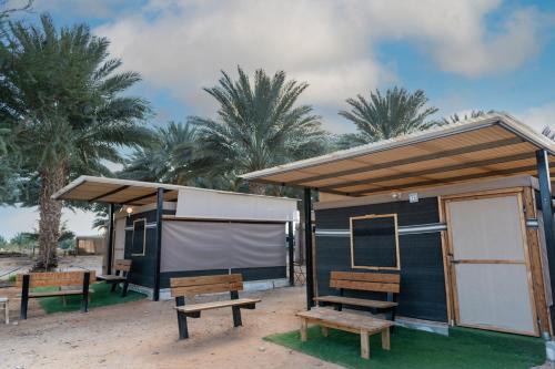 a black building with benches in front of palm trees at Ras Hasita in H̱aẕeva