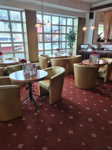 a dining room with tables and chairs and windows at Hotel Montenegro in Bruntál