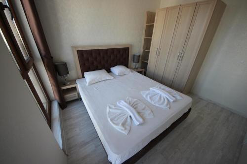 een slaapkamer met een bed met witte lakens en kussens bij Menada Harmony Suites X in Boergas