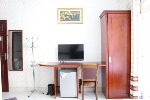 a room with a table with a tv on a wall at Mai Guest House in Ho Chi Minh City