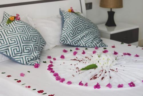 a plate with flowers on a bed with two pillows at Fiyala Homestay in Feydhoo