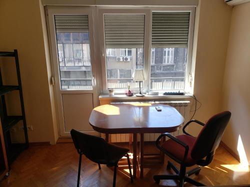 a room with a table and chairs and two windows at Private cozy room 2 with shared kitchen in appartment in Belgrade