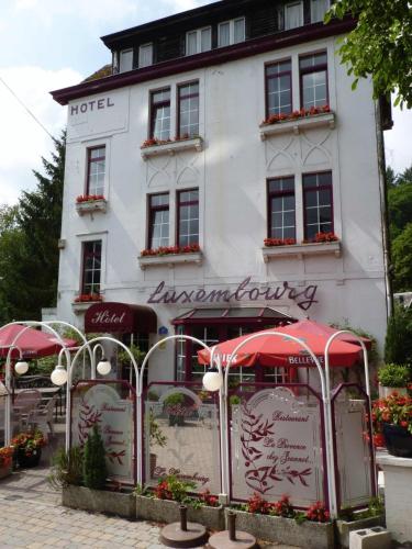 a white building with red umbrellas in front of it at Hotel Le Luxembourg in La Roche-en-Ardenne