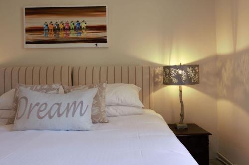 Una cama con una almohada con la palabra sueño en ella en Le Manoir du Mûrier, en Boisredon
