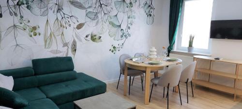 Apartament Botanika في سوبوت: غرفة معيشة مع طاولة وأريكة خضراء