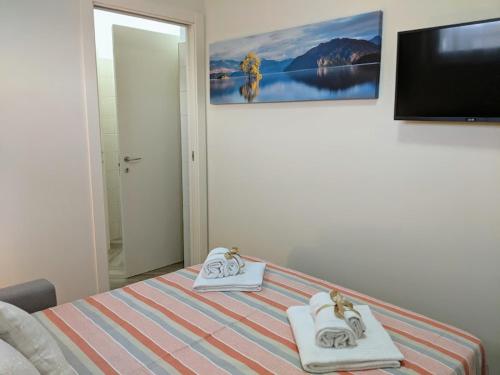 a bedroom with a bed with towels and a flat screen tv at Il Giglio Marino Cilento Residence by ElodeaGroup in Ascea