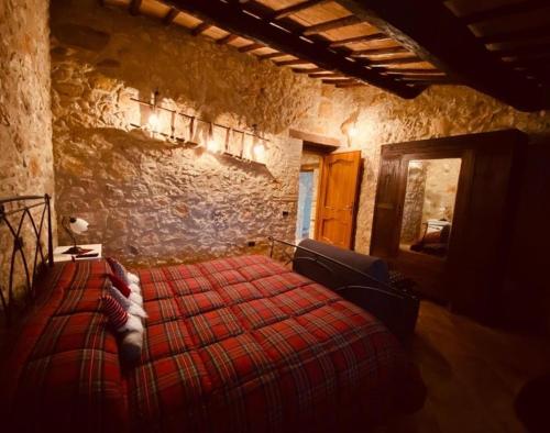a bedroom with a red bed in a stone wall at B&B Fontanelle in Alviano