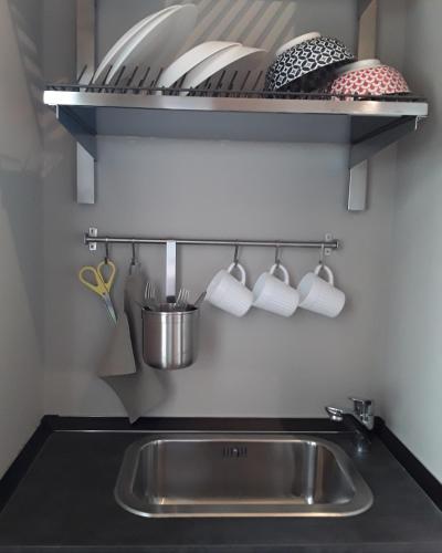 a kitchen sink and a shelf with cups and utensils at Casatitta Bed & Breakfast in Milan