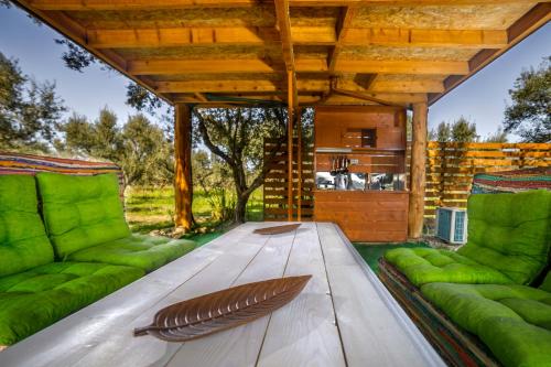 a wooden table with green cushioned chairs and a wooden bench at FairyTale in Koukounariá