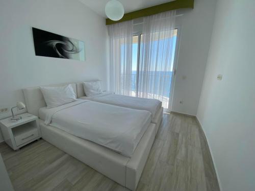 a white bedroom with a bed and a window at Nautilus Apartments in Dobra Voda