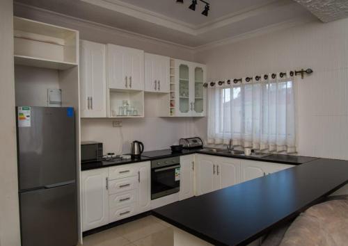 uma cozinha com armários brancos e um balcão preto em 848 Guest House em Victoria Falls