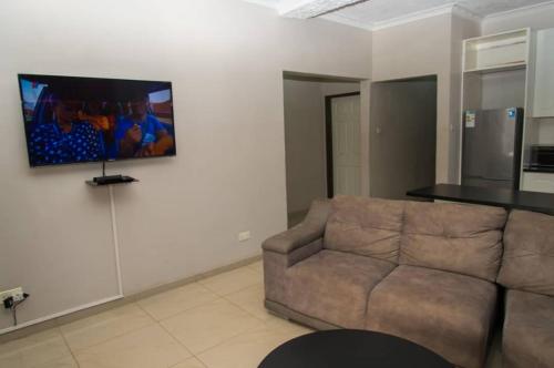 sala de estar con sofá y TV en la pared en 848 Guest House, en Victoria Falls