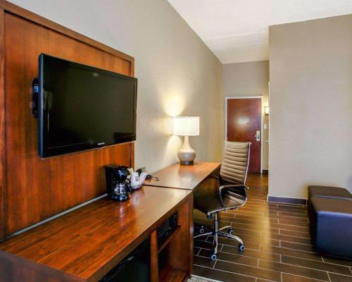 a hotel room with a desk with a television on a wall at Comfort Suites Georgetown in Georgetown