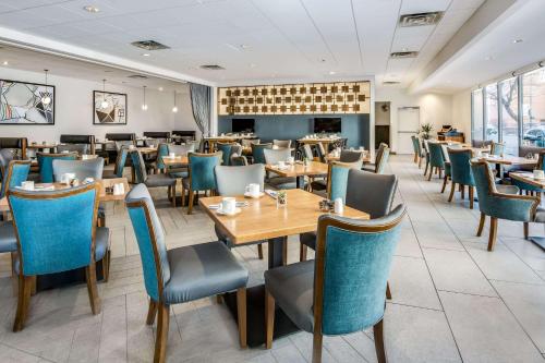 Sonesta Denver Downtown في دنفر: مطعم بطاولات خشبية وكراسي زرقاء