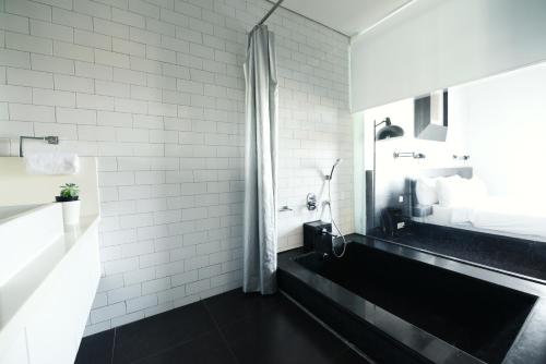 a black and white bathroom with a sink and a shower at Morrissey Hotel in Jakarta