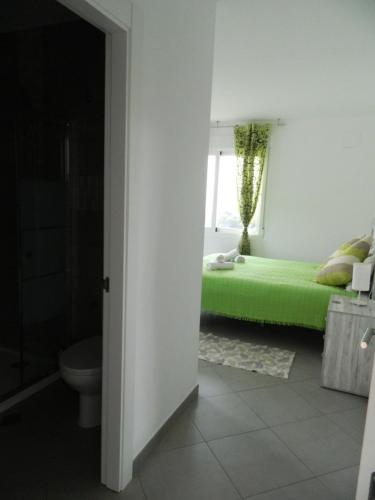 a bedroom with a green bed and a window at Hotel Restaurant Baladrar in Benissa