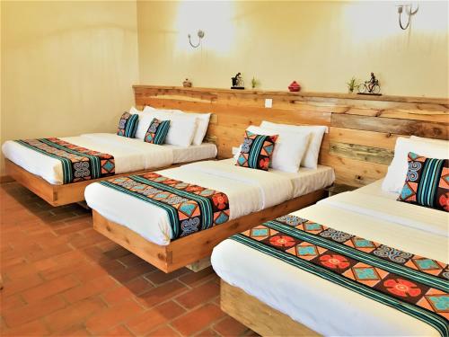 3 camas en una habitación con paredes de madera en Kaswa Lodge en Fort Portal