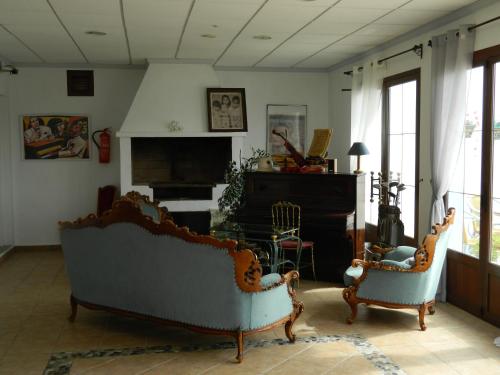a living room with two chairs and a piano at Hotel Restaurant Baladrar in Benissa
