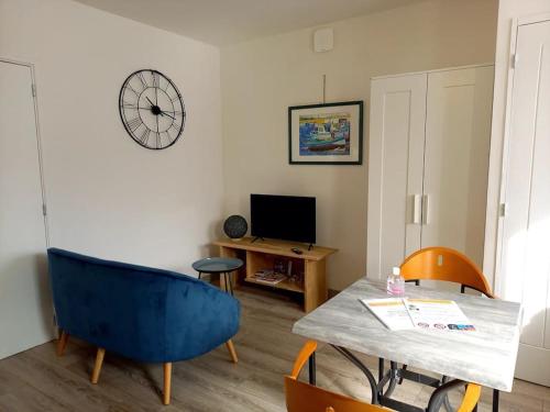 Una sala de estar con una mesa y un reloj en la pared. en Gîte "Chez Albert et Cie"- 8 mn du Puy du Fou, en Les Herbiers