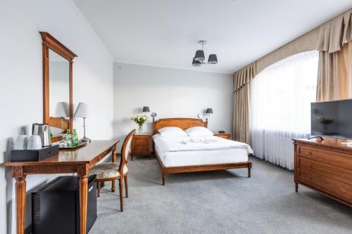 a bedroom with a bed and a desk and a television at Hotel Pod Złotą Różą in Kielce