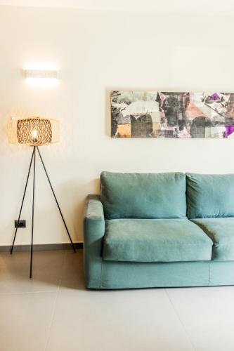 a blue couch in a living room with a lamp at Gazzi Apartments 'Panoramic & Relaxing' in Arco