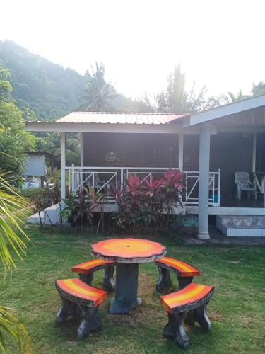 une table de pique-nique et deux tabourets devant une maison dans l'établissement Juara Cottage, à l'Île Tioman