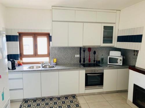a kitchen with white cabinets and a sink and a microwave at Anjú-Pardal in Mogadouro