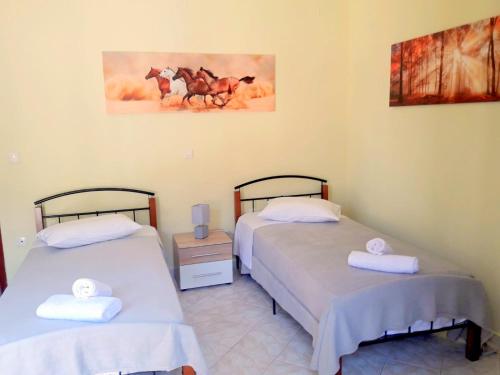 a room with two beds and a painting of horses at Dourios Ippos Apartments in Frikes